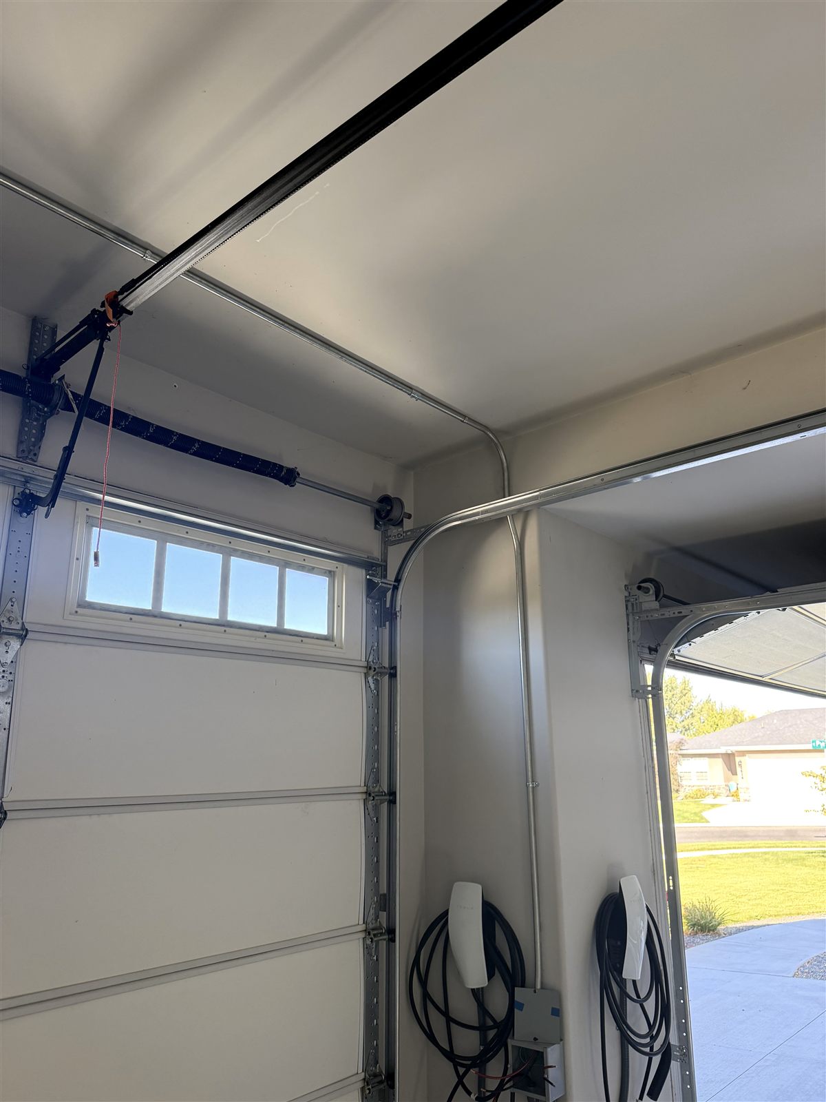 Metal conduit routed across a garage ceiling to two wall-mounted EV chargers
